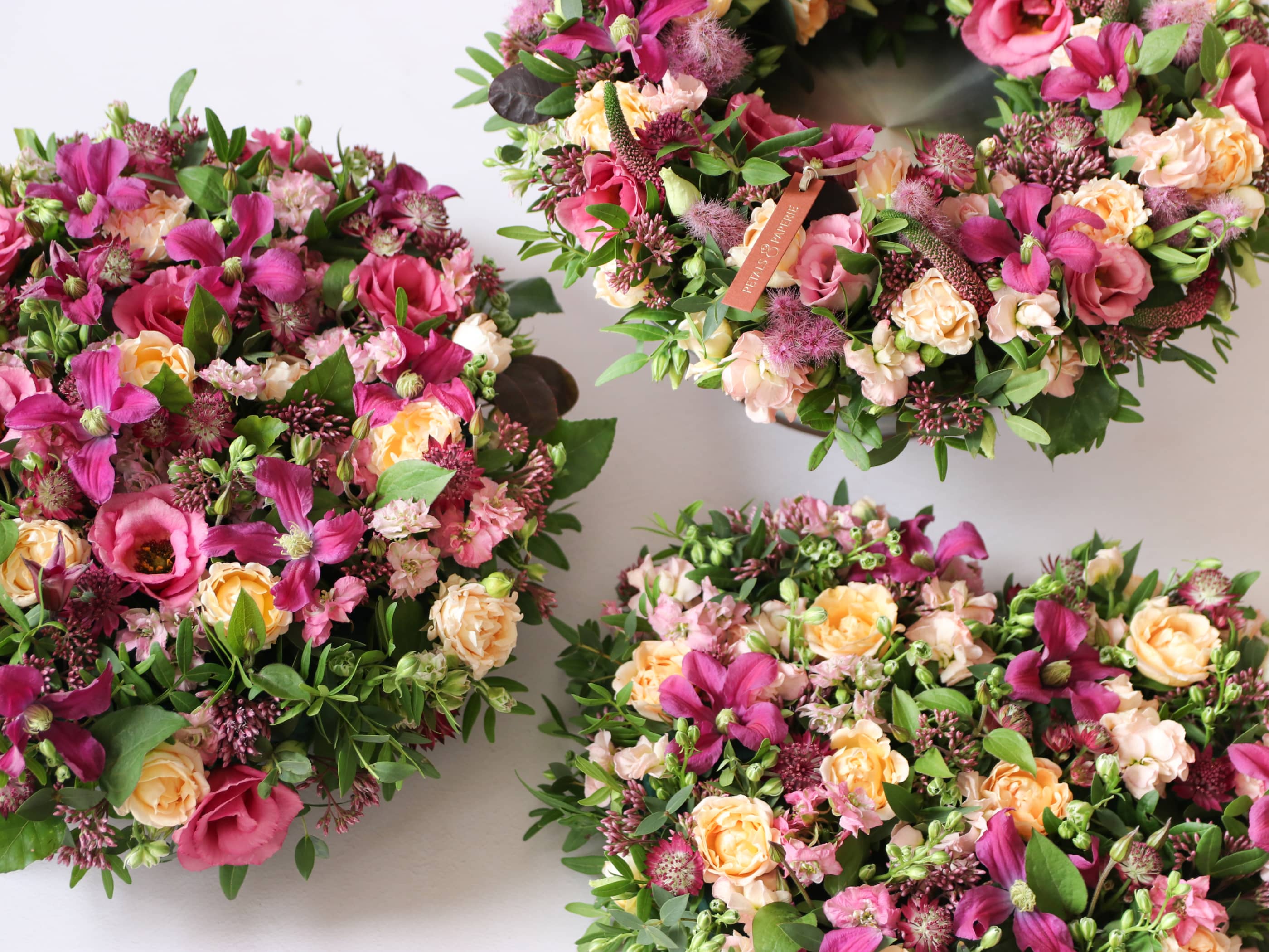 A selection of funeral arrangements including a wreath, round posy and heart posy in a vibrant and bright selection of colours.