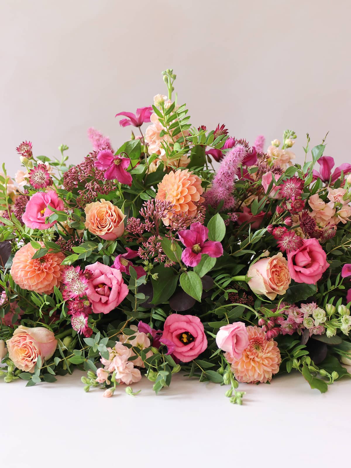 Double ended coffin spray of pink, orange, and green flowers on a white background