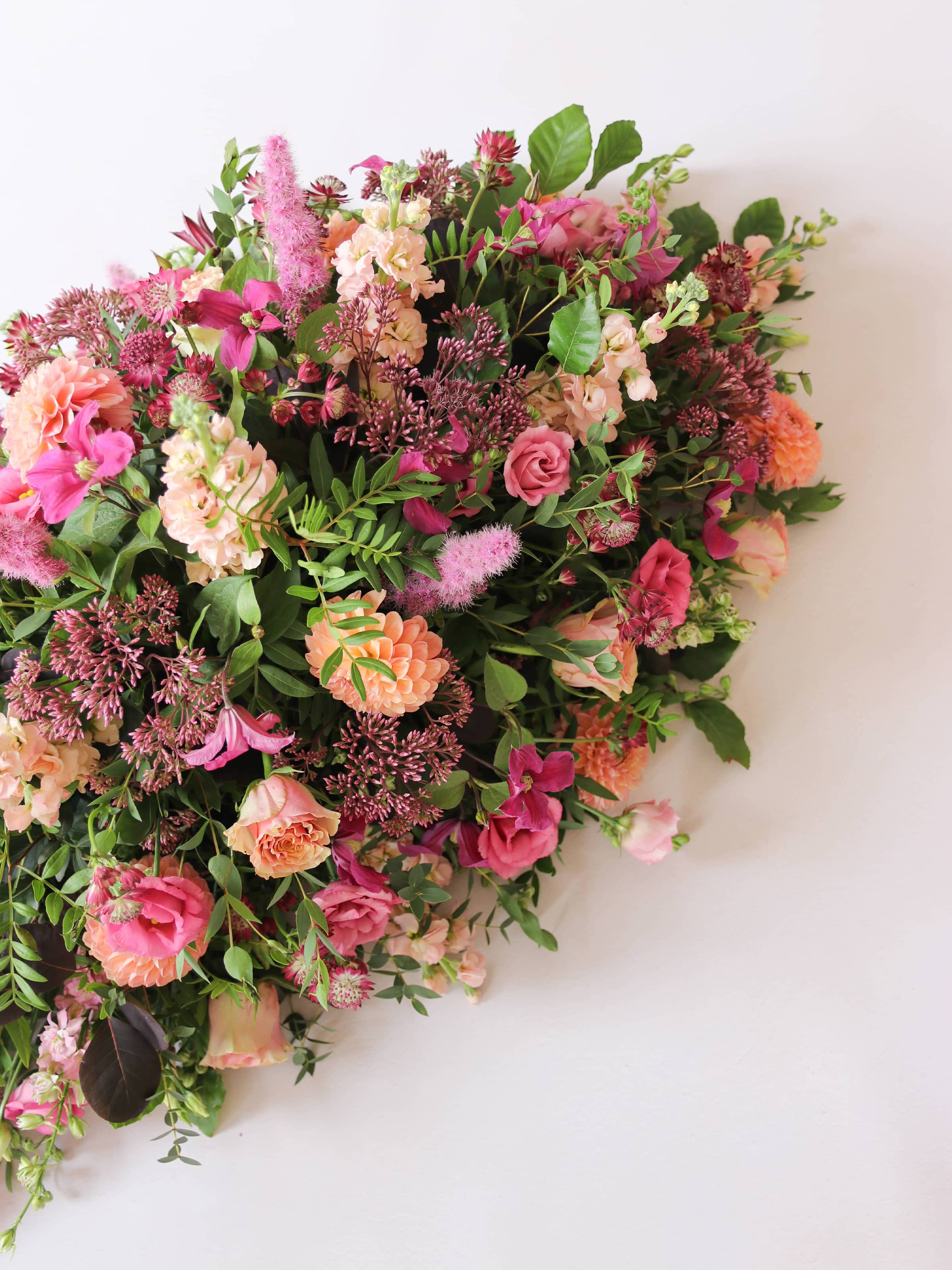 One end of a bright pink and peach coffin spray on a white background