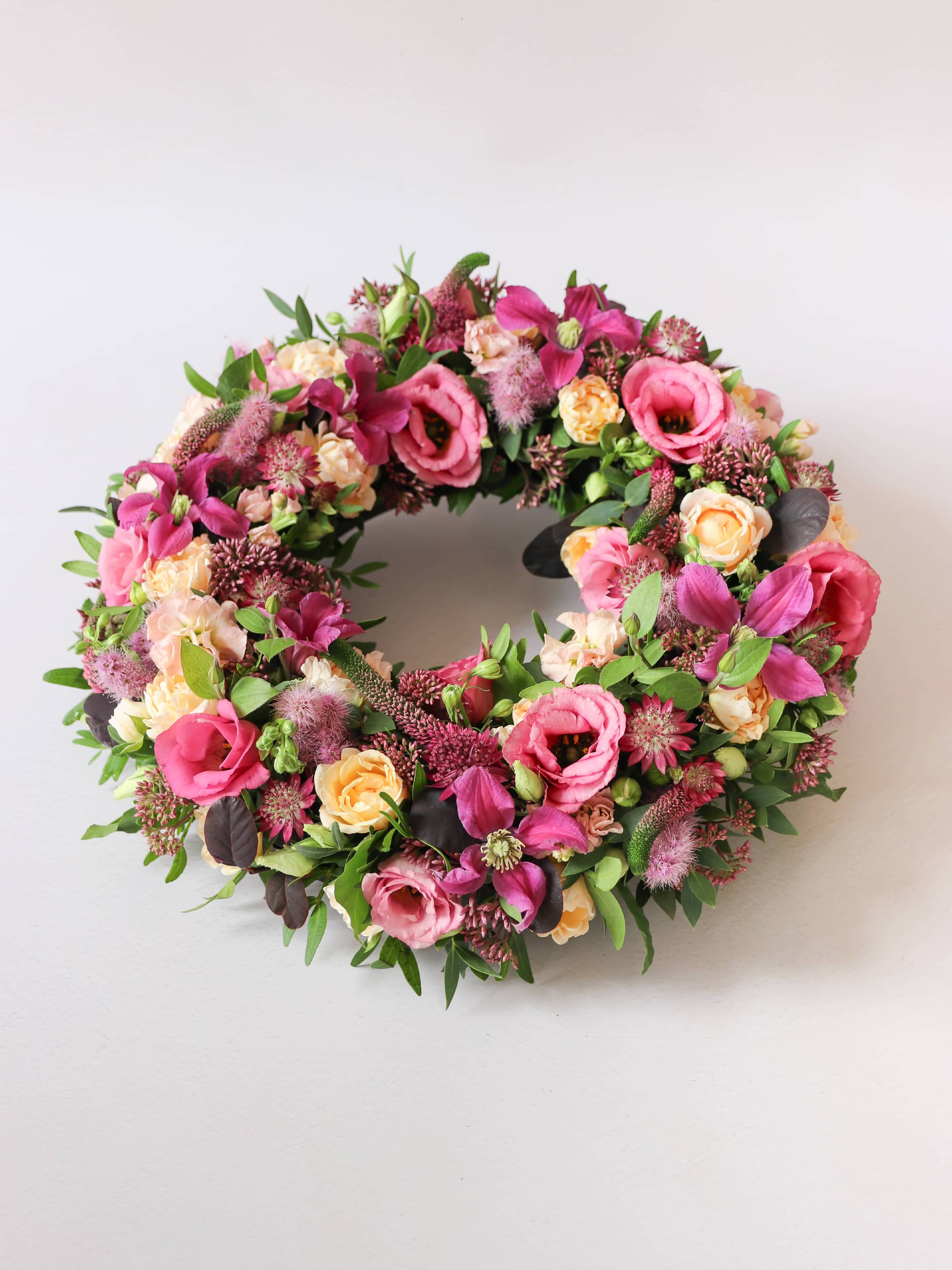 Floral wreath with pink, yellow, and green flowers on a white background