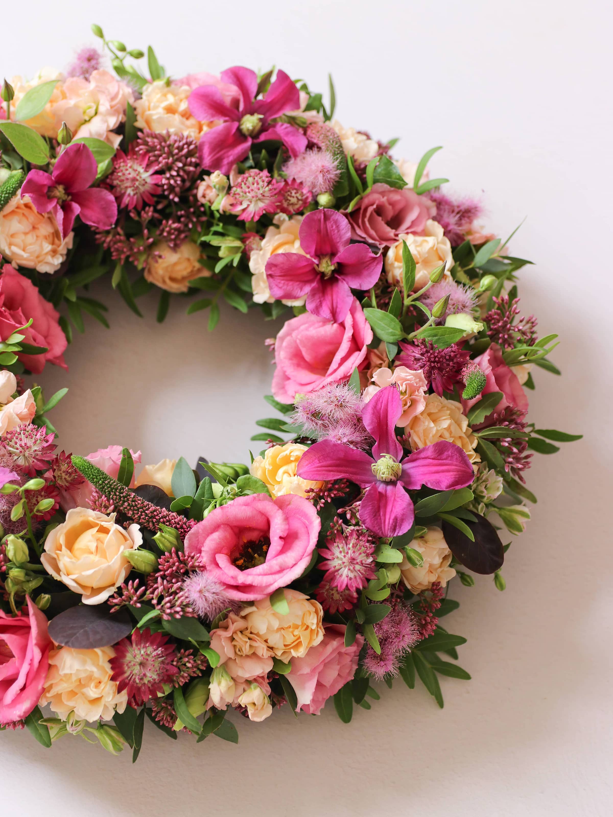 Side shot of a floral wreath with pink, yellow, and green flowers on a white background