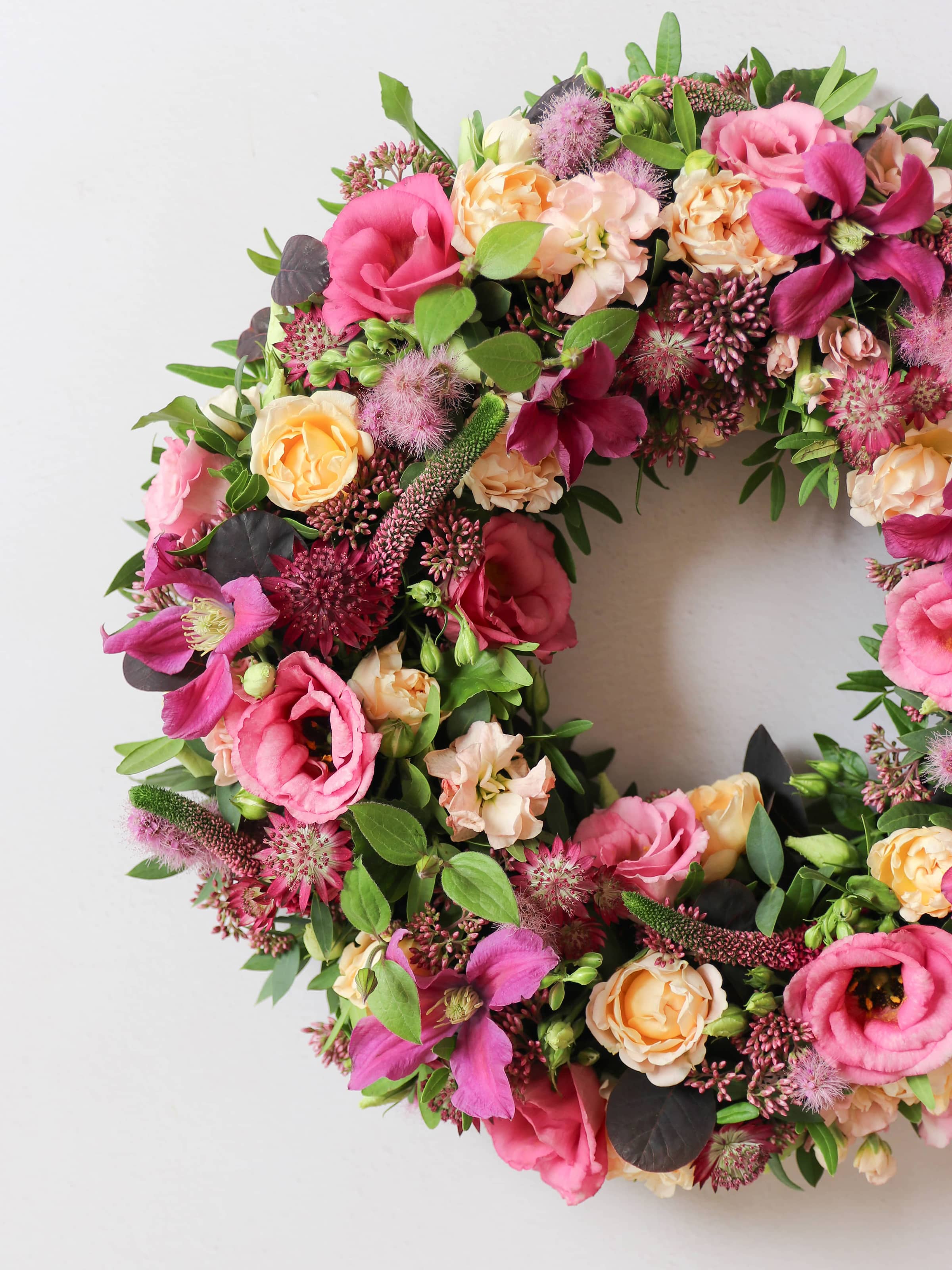 Floral wreath with pink, red, and yellow flowers on a white background