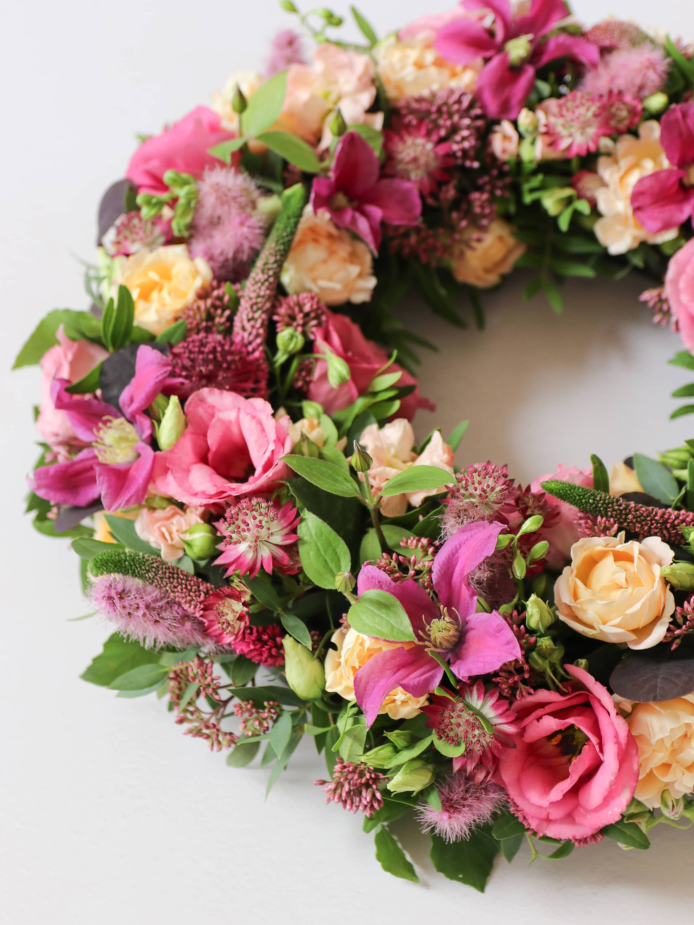 Floral wreath with pink, purple, and yellow flowers on a white background