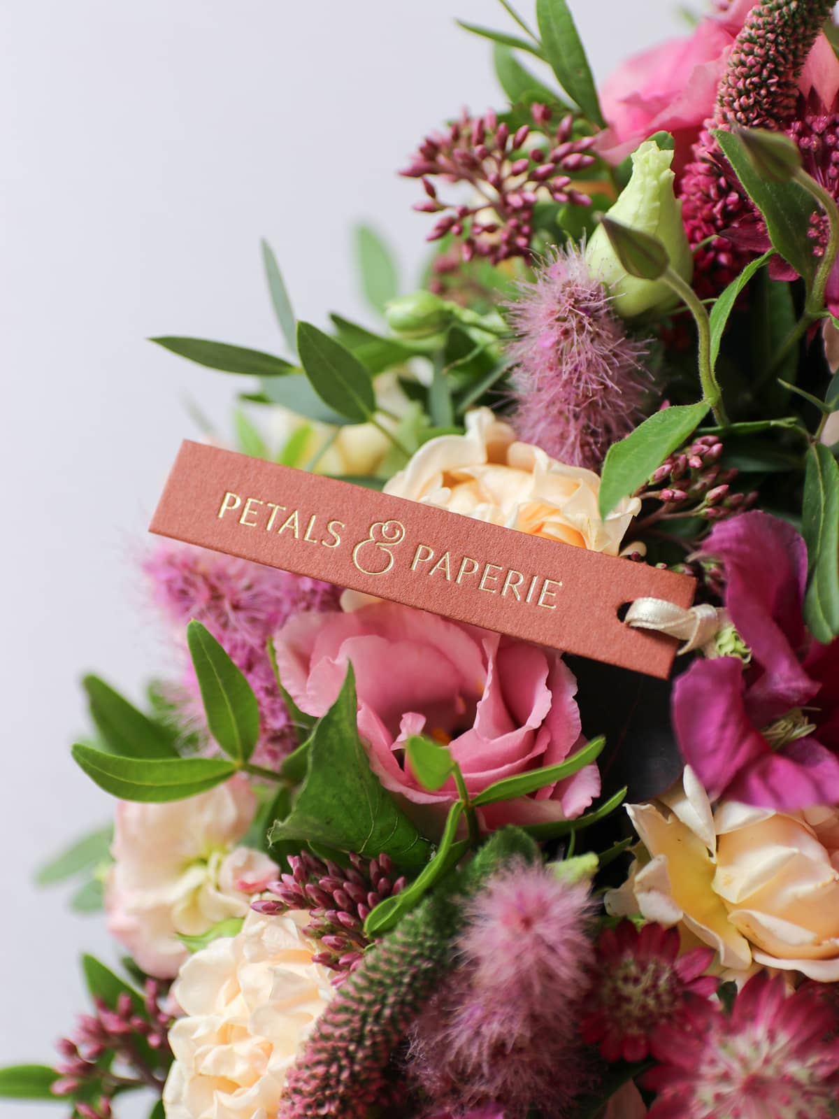 Floral arrangement with a 'Petals & Paperie' sign on a light background