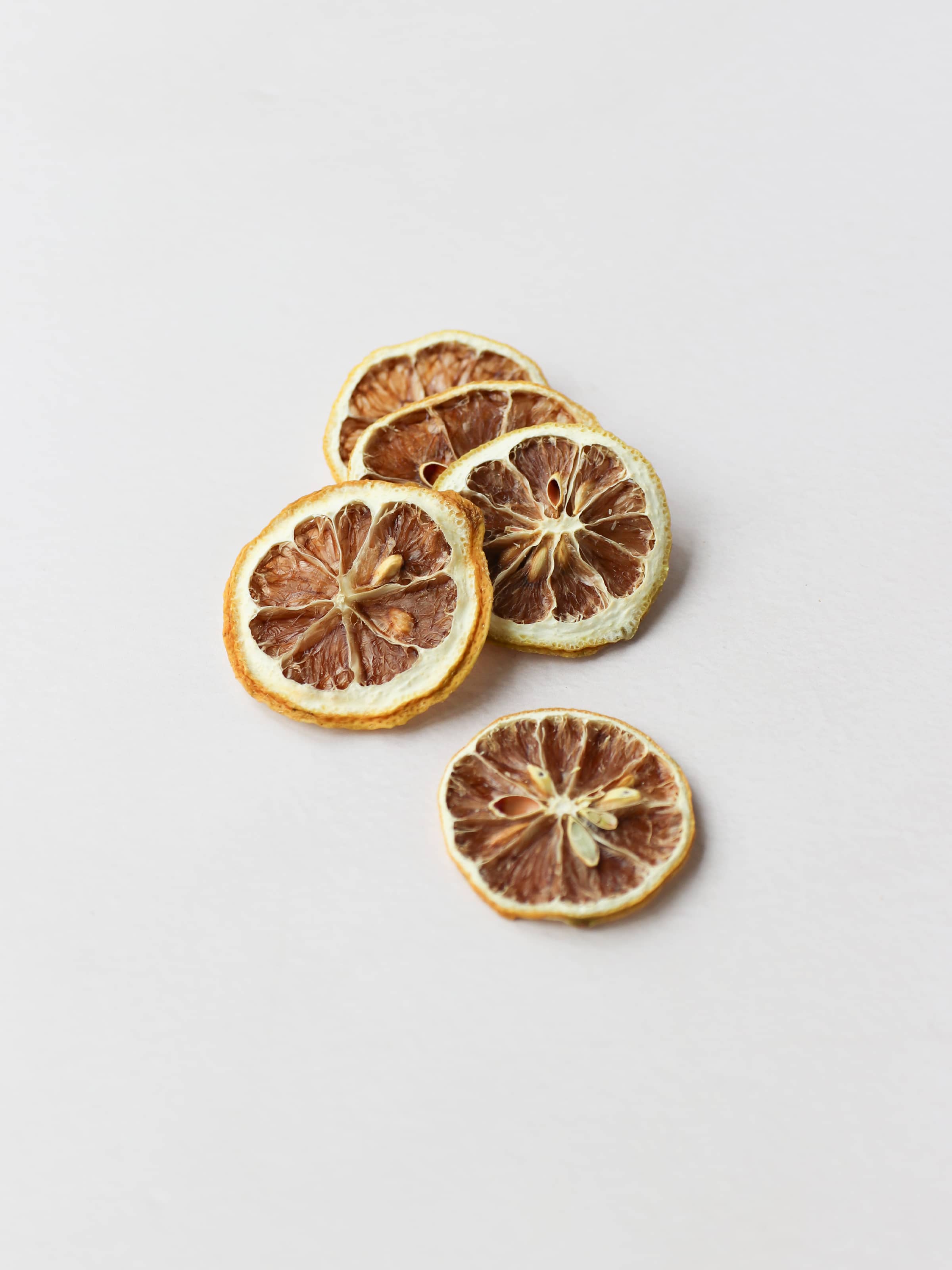 5 dried lemon slices stacked on a light neutral background.