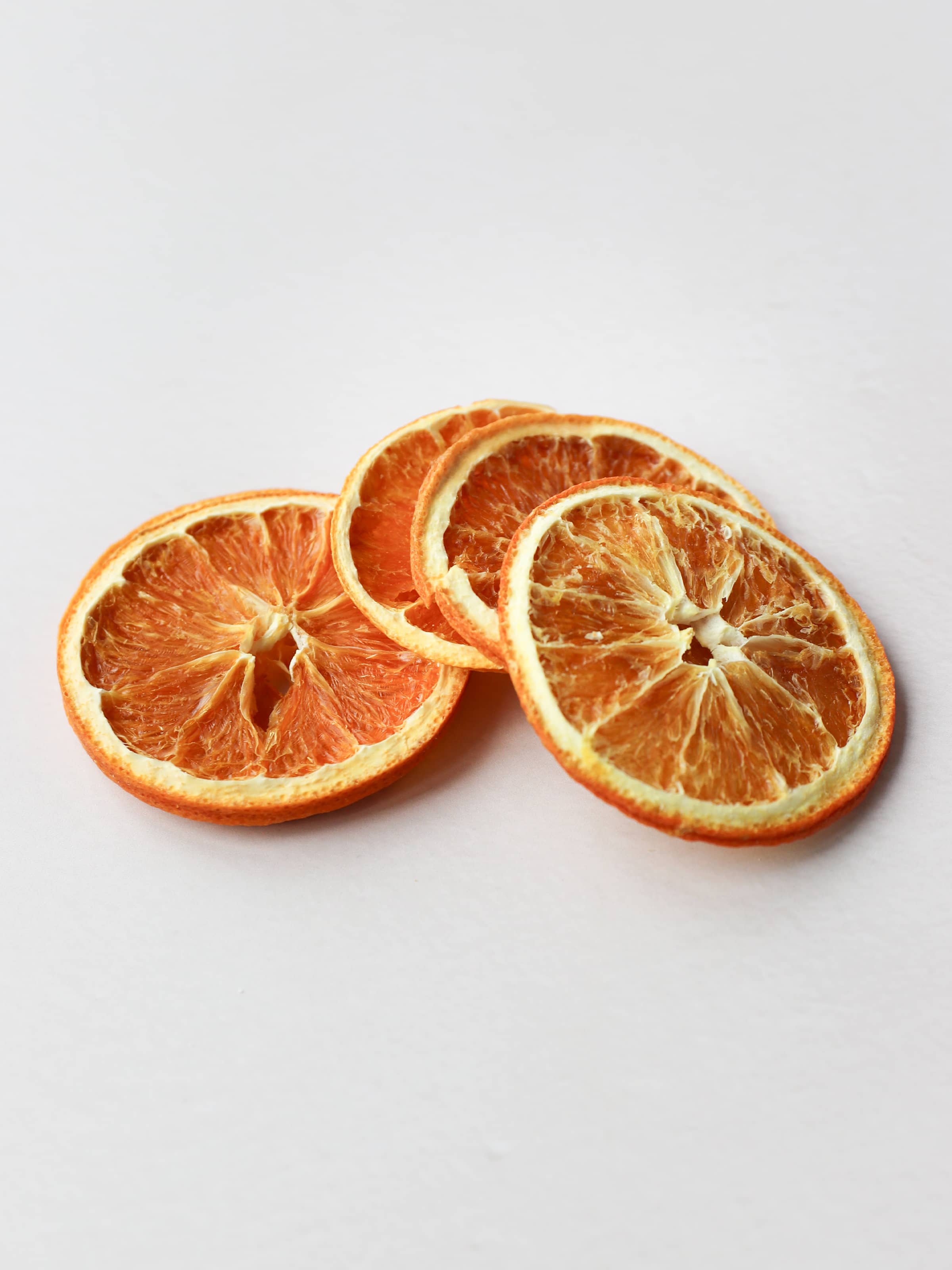 Five dried orange slices for Christmas wreath making, stacked on a light background.