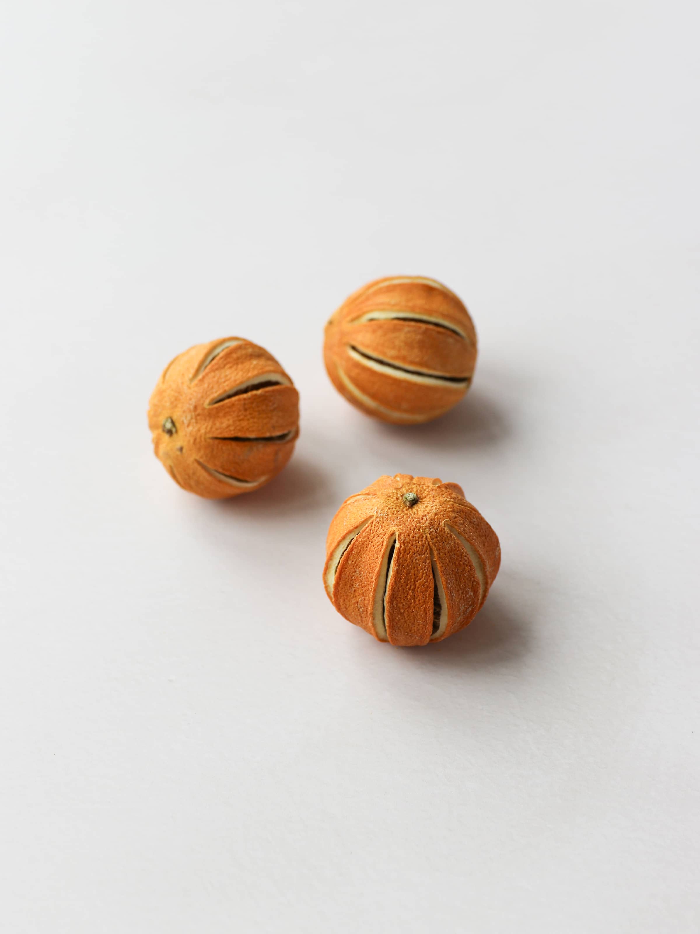 Three dried whole oranges for Christmas wreath making, positioned on a light background.