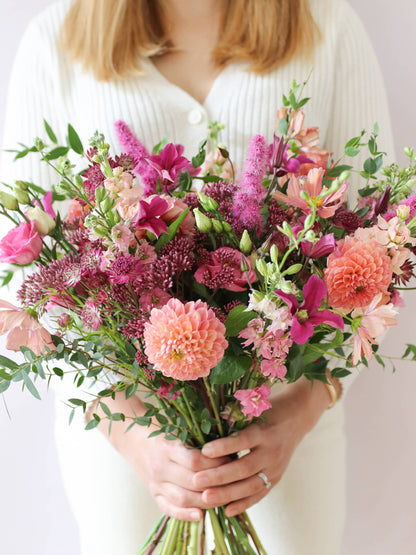 Person holding a bouquet of bright and pink flowers
