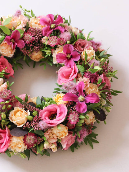 Side shot of a floral wreath with pink, yellow, and green flowers on a white background