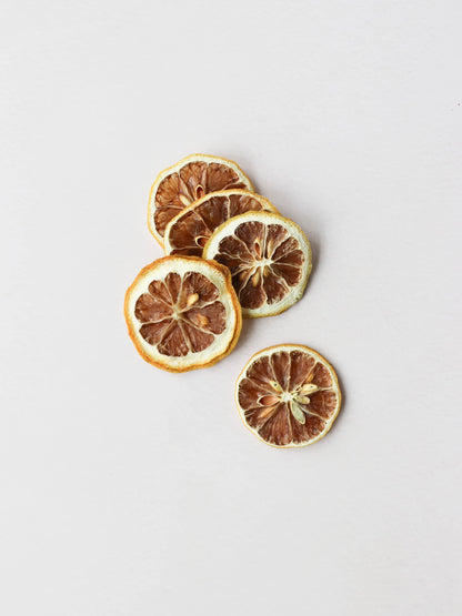 A top view of 5 dried lemon slices on a light neutral background.