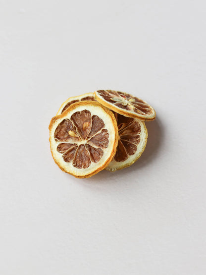 A top view of 5 dried lemon slices stacked on a light neutral background.