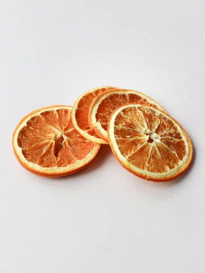 Five dried orange slices for Christmas wreath making, stacked on a light background.