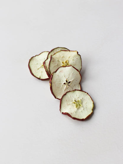 A stack of dried red apple slices for Christmas wreath making lying on a light background.
