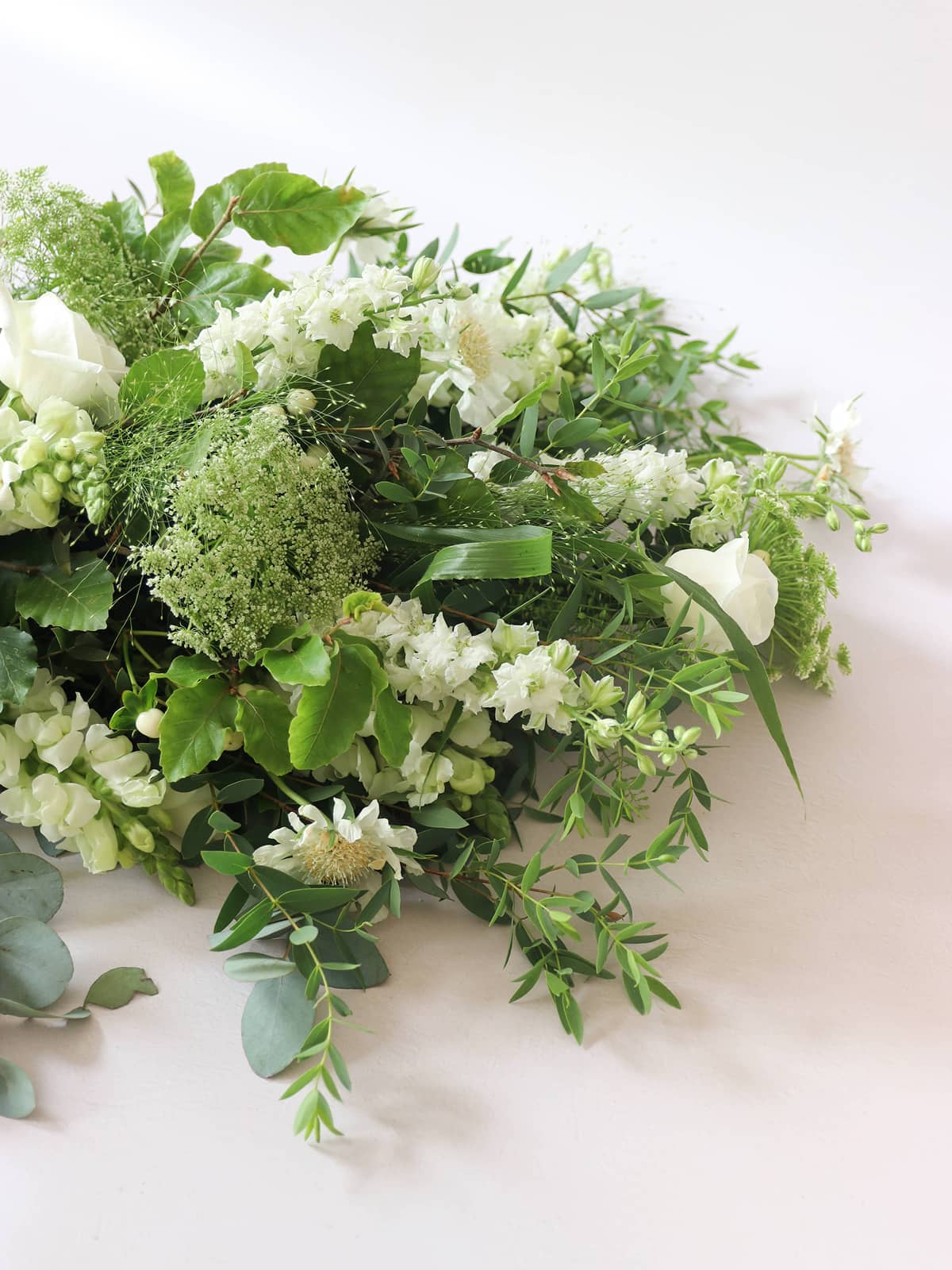 Funeral sheaf of green and white flowers on a light background
