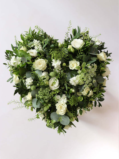 Heart shaped funeral posy with white and green flowers on a white background