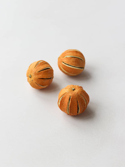 Three dried whole oranges for Christmas wreath making, positioned on a light background.